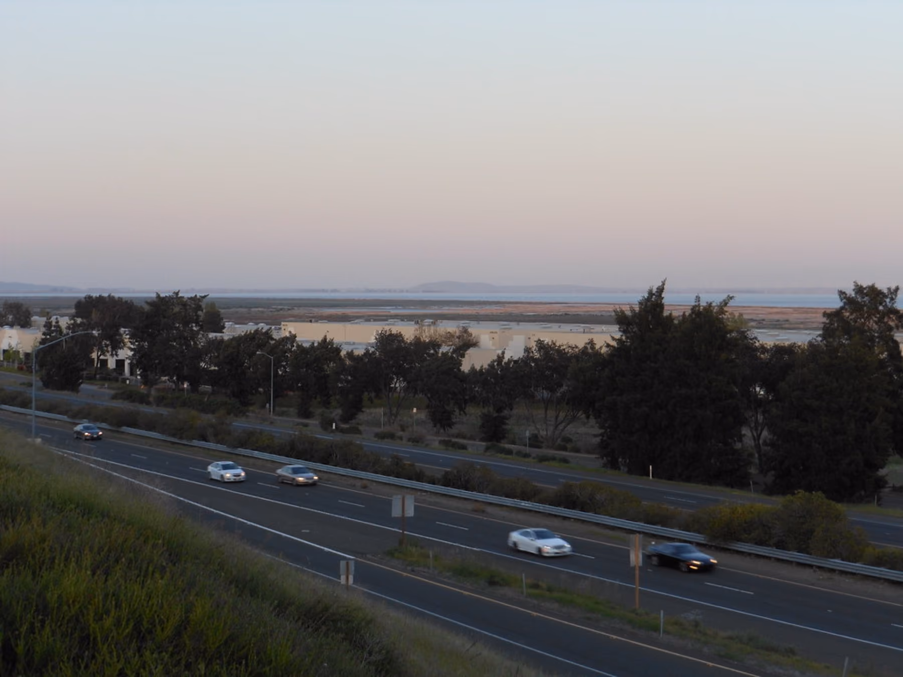 Highway traffic in the foreground with the flat water of Suisun Bay and its marshes behind.