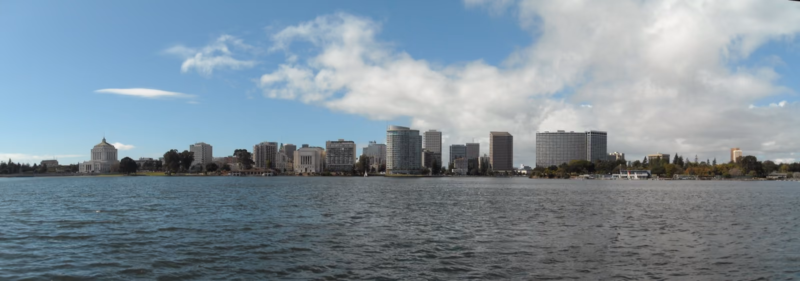 Downtown towers along the far shore of a wide lake under a cloudy sky.