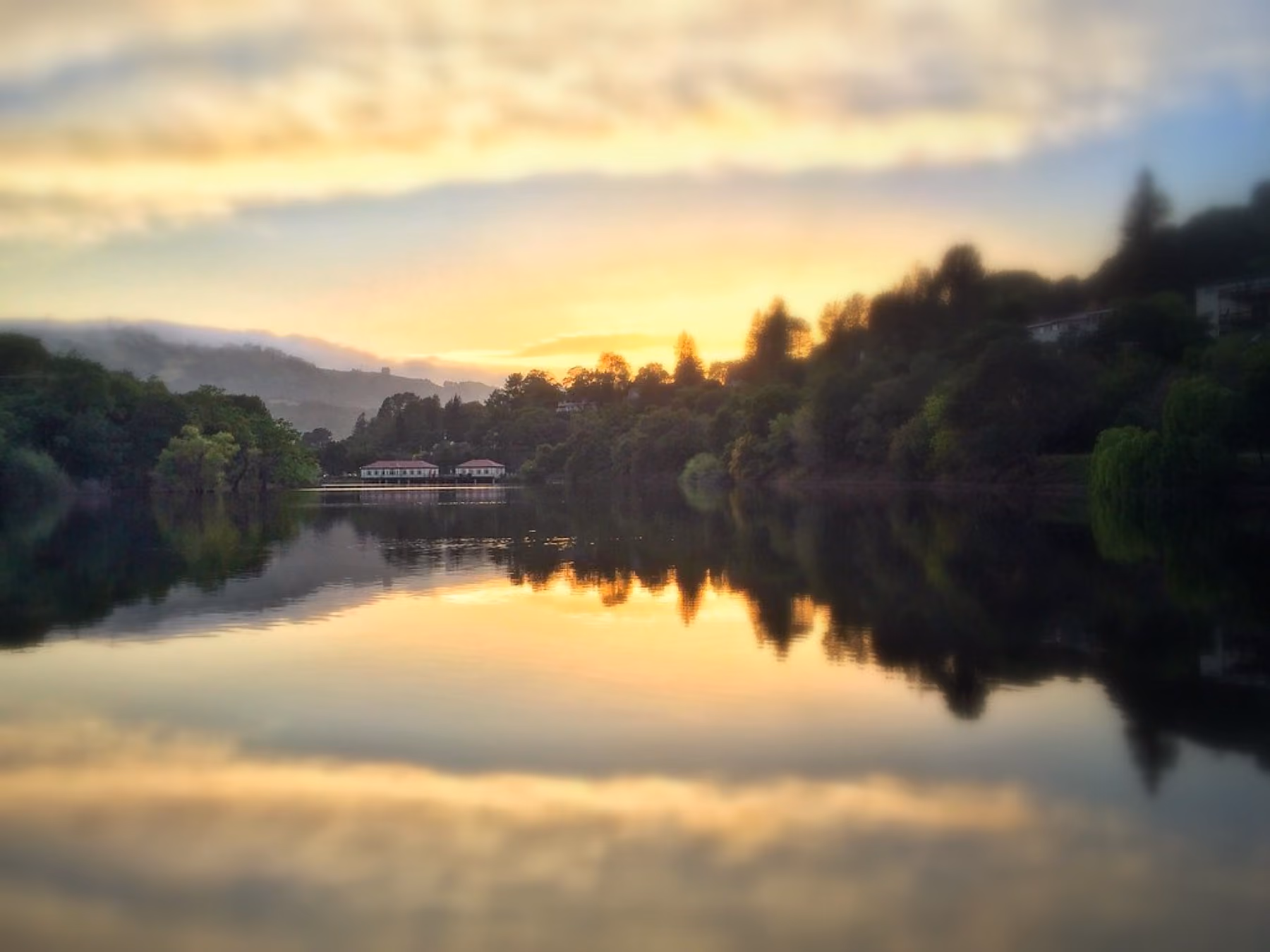Lake Cascade at dusk, trees and a boathouse reflected in still water.